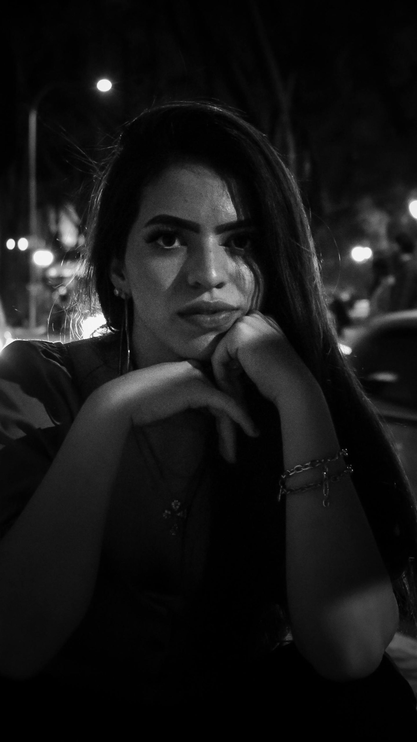 Captivating black and white portrait of a woman in a night setting with moody lighting.