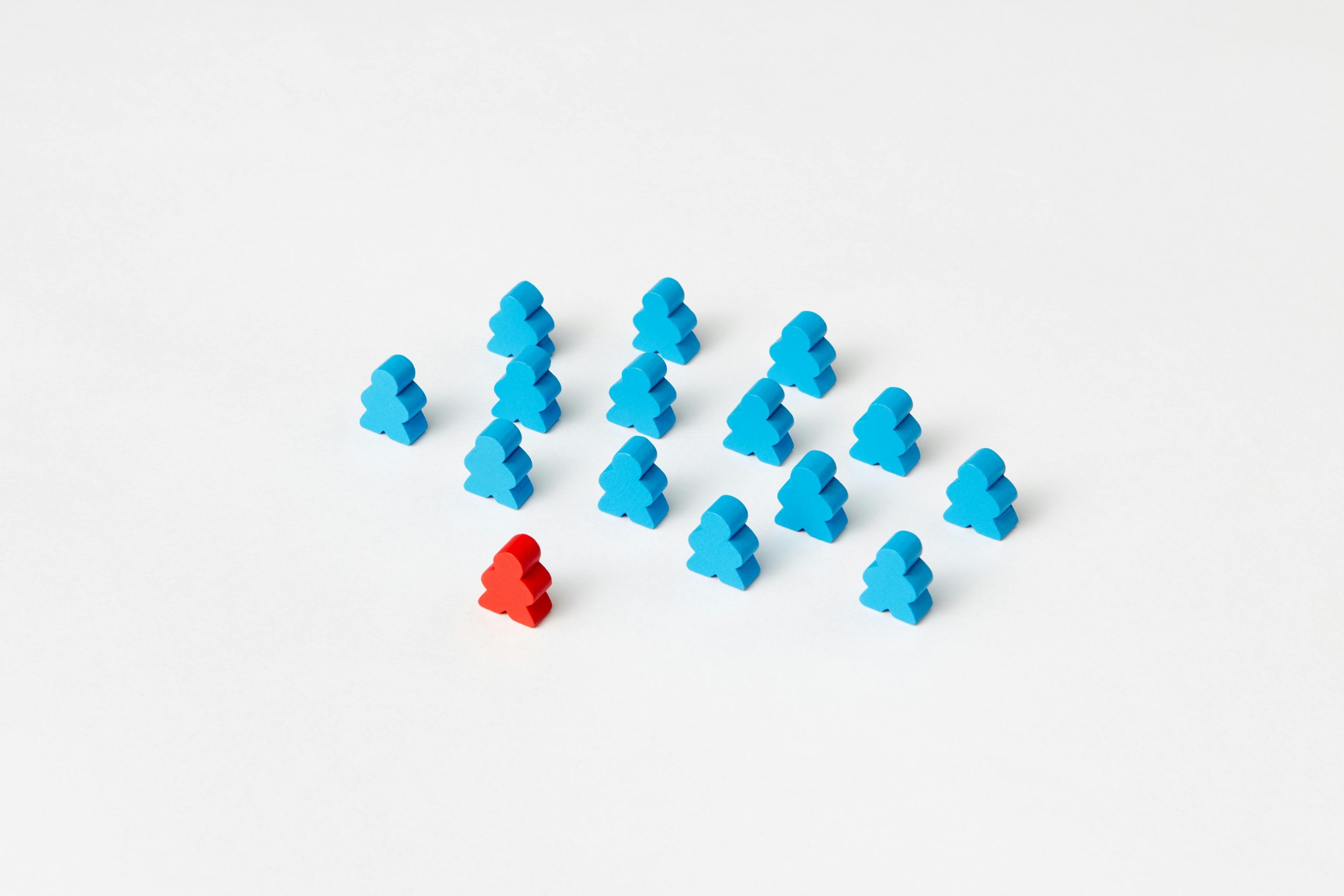 A collection of blue meeple figures with a standout red one on a white background.
